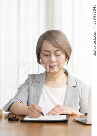一位老年婦女簽署並蓋章了一份合約。 一位老年婦女簽署並蓋章了一份合約。 138451045