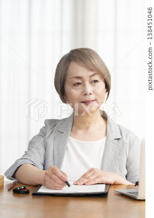 一位老年婦女簽署並蓋章了一份合約。 一位老年婦女簽署並蓋章了一份合約。 138451046