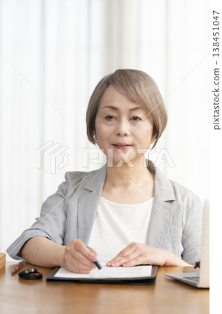 一位老年婦女簽署並蓋章了一份合約。 一位老年婦女簽署並蓋章了一份合約。 138451047