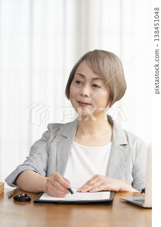 一位老年婦女簽署並蓋章了一份合約。 一位老年婦女簽署並蓋章了一份合約。 138451048
