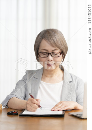 A senior woman signs and seals a contract. 138451053