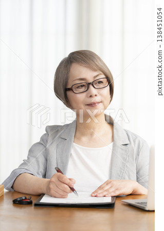 一位老年婦女簽署並蓋章了一份合約。 一位老年婦女簽署並蓋章了一份合約。 138451054