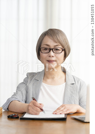 一位老年婦女簽署並蓋章了一份合約。 一位老年婦女簽署並蓋章了一份合約。 138451055
