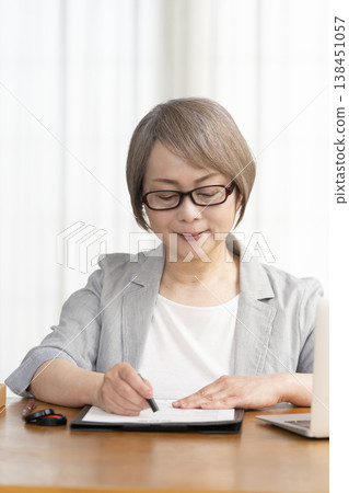 一位老年婦女簽署並蓋章了一份合約。 一位老年婦女簽署並蓋章了一份合約。 138451057