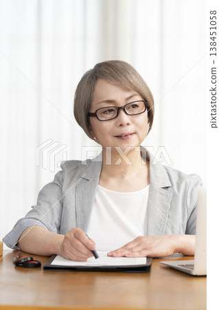 一位老年婦女簽署並蓋章了一份合約。 一位老年婦女簽署並蓋章了一份合約。 138451058
