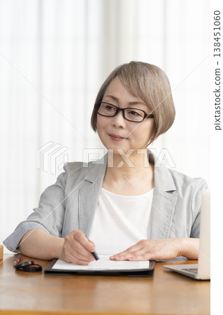 一位老年婦女簽署並蓋章了一份合約。 一位老年婦女簽署並蓋章了一份合約。 138451060