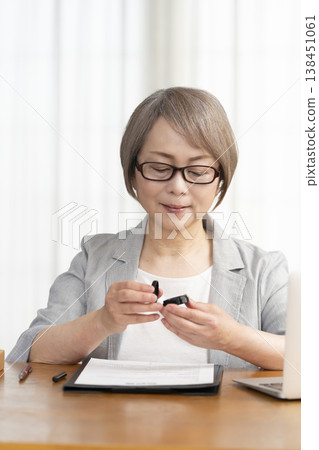 A senior woman signs and seals a contract. 138451061