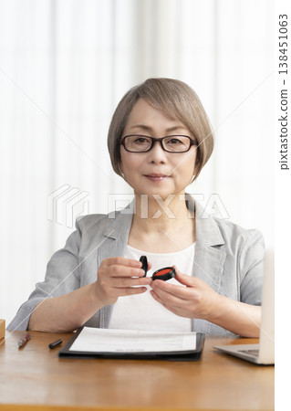 一位老年婦女簽署並蓋章了一份合約。 一位老年婦女簽署並蓋章了一份合約。 138451063