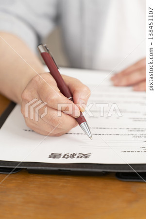 一位老婦人在合約上簽字蓋章時的手。 一位老婦人在合約上簽字蓋章時的手。 138451107