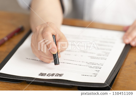 一位老婦人在合約上簽字蓋章時的手。 一位老婦人在合約上簽字蓋章時的手。 138451109