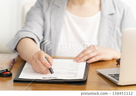 一位老婦人在合約上簽字蓋章時的手。 一位老婦人在合約上簽字蓋章時的手。 138451112