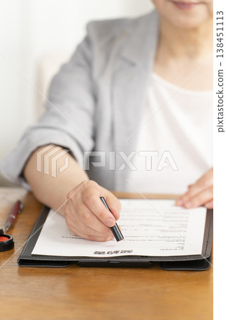 一位老婦人在合約上簽字蓋章時的手。 138451113