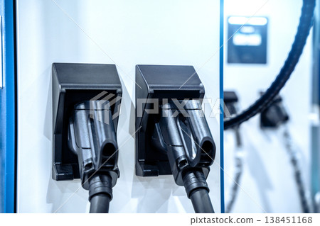 Electric car charging on parking lot with electric car charging station on city street. Close up of power supply plugged into an electric car being charged. Electric car charging on parking lot with electric car charging station on city street. Close up of power supply plugged into an electric car being charged. 138451168