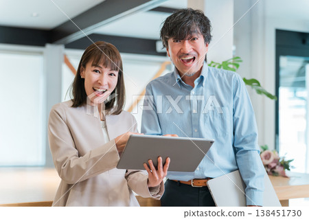 Businesswomen and businessmen happy to look at a tablet (improved performance, profit, results, success, increased sales) 138451730
