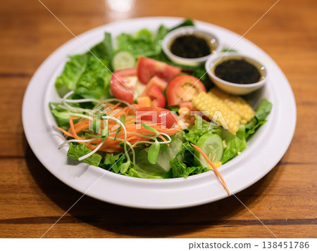 Fresh Mixed Garden Salad with Dressing on Wooden Table and Copy Space Fresh Mixed Garden Salad with Dressing on Wooden Table and Copy Space 138451786
