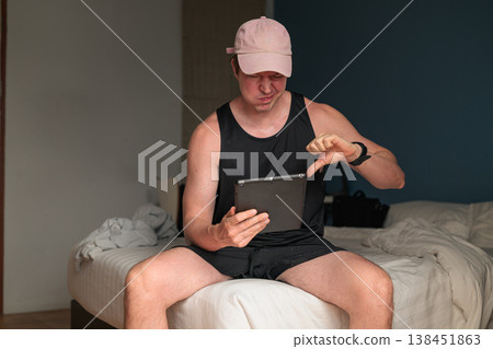 Disappointed Caucasian Man with Tablet Giving Thumbs Down Gesture on Bed 138451863