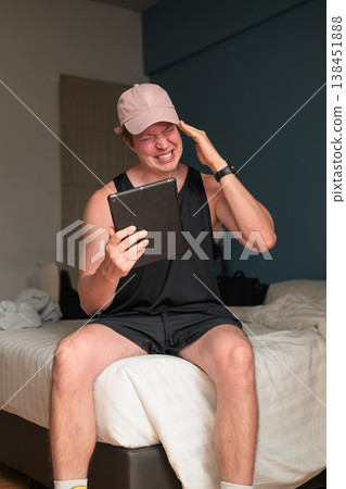 Caucasian Man with Headache Migraine Using Tablet on Bed in Minimalist Bedroom Caucasian Man with Headache Migraine Using Tablet on Bed in Minimalist Bedroom 138451888