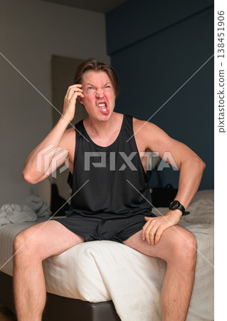 Funny Caucasian Man Scratching Head on Bed in Minimalist Bedroom Funny Caucasian Man Scratching Head on Bed in Minimalist Bedroom 138451906
