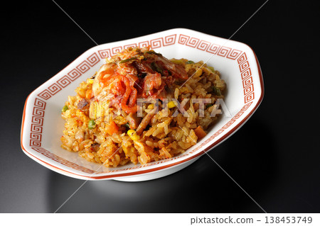 Spicy kimchi fried rice photographed alone against a black background. 138453749