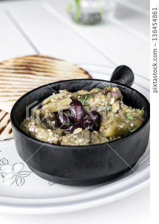 Roasted mashed Eggplant tapas snack on white table in outdoor restaurant in greece Roasted mashed Eggplant tapas snack on white table in outdoor restaurant in greece 138454861