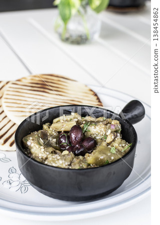 Roasted mashed Eggplant tapas snack on white table in outdoor restaurant in greece Roasted mashed Eggplant tapas snack on white table in outdoor restaurant in greece 138454862