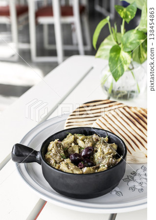 Roasted mashed Eggplant tapas snack on white table in outdoor restaurant in greece 138454863