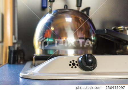 Kettle and pots on a kitchen stove with a control knob visible in caravan during daytime cooking activities Kettle and pots on a kitchen stove with a control knob visible in caravan during daytime cooking activities 138455097