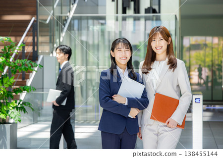 一對年輕男女穿著西裝，面帶微笑。 138455144