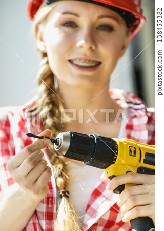 Woman using drill on window 138455382