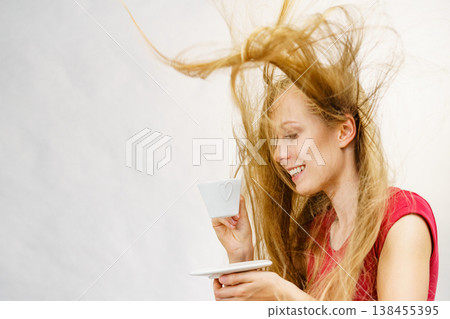 Blonde girl blowing hair holds coffee cup 138455395