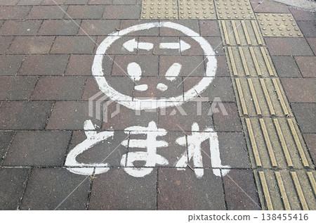 A road marking on an asphalt sidewalk with a white line indicating "STOP" and a footprint. 138455416