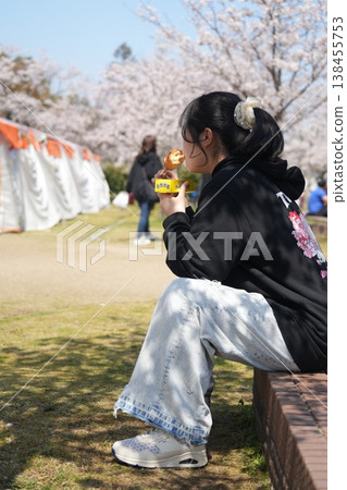 一個女孩坐在長椅上欣賞櫻花。 138455753