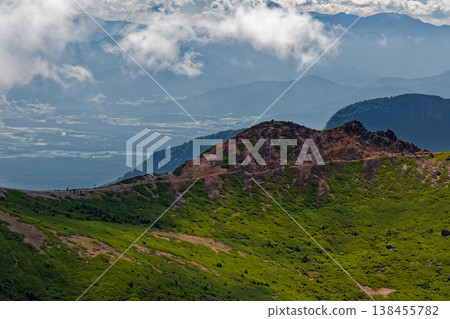 A view of hikers on the ridgeline from Nishitengudake in the Yatsugatake mountain range, and the cloud-covered mountain range of Okuchichibu. 138455782