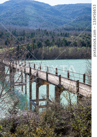 Wooden bridge over turquoise lake with forest and mountains in Spain scenic nature landscape Wooden bridge over turquoise lake with forest and mountains in Spain scenic nature landscape 138456653