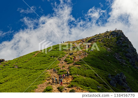 The cloud-covered Yatsugatake mountain range and Higashi-Tengudake as seen from the saddle between Nishi-Tengudake and Higashi-Tengudake. 138456770