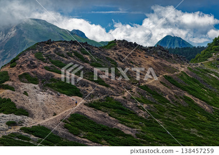 View of Mt. Neishi and the main peaks of the Yatsugatake mountain range shrouded in clouds, seen from the descent of Mt. Higashi-Tengudake. 138457259