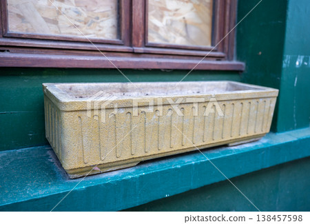Old concrete window planter on green facade empty flower box with wooden frame window urban exterior detail Old concrete window planter on green facade empty flower box with wooden frame window urban exterior detail 138457598