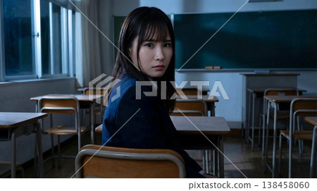 A female student in a school uniform looks back at me from her seat in a darkened classroom. A female student in a school uniform looks back at me from her seat in a darkened classroom. 138458060