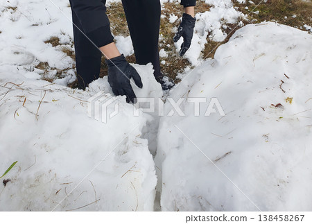 A man in black gloves carefully pushes apart handmade snow blocks A man in black gloves carefully pushes apart handmade snow blocks 138458267