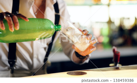Bartender pouring refreshing drink with ice into glass 138459386