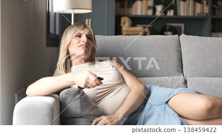 Bored transgender woman using remote control while watching TV Bored transgender woman using remote control while watching TV 138459422