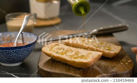 Olive oil being poured on bread slices for sandwich in kitchen at home Olive oil being poured on bread slices for sandwich in kitchen at home 138459469