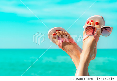 Upside woman feet and red pedicure wearing pink sandals, sunglasses at seaside. Funny and happy fashion young woman relax on vacation. Chill out girl at beach. Creative for tour agent. Weekend travel. Upside woman feet and red pedicure wearing pink sandals, sunglasses at seaside. Funny and happy fashion young woman relax on vacation. Chill out girl at beach. Creative for tour agent. Weekend travel. 138459816