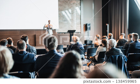 Speaker giving a talk in conference hall at business event. Rear view of unrecognizable people in audience at the conference hall. Business and entrepreneurship concept Speaker giving a talk in conference hall at business event. Rear view of unrecognizable people in audience at the conference hall. Business and entrepreneurship concept 138459965