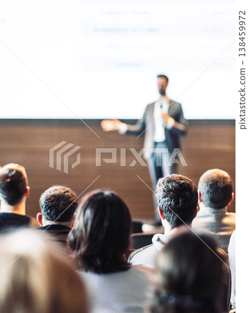 Speaker giving a talk in conference hall at business event. Rear view of unrecognizable people in audience at the conference hall. Business and entrepreneurship concept Speaker giving a talk in conference hall at business event. Rear view of unrecognizable people in audience at the conference hall. Business and entrepreneurship concept 138459972