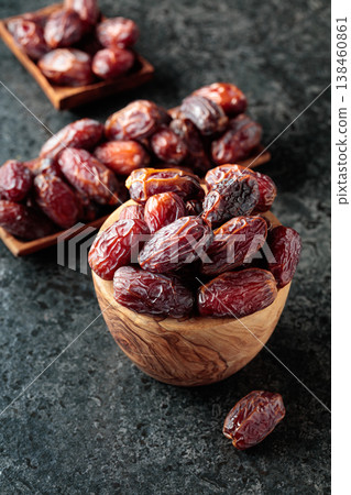 Dried dates fruit in wooden bowl on a black table. Dried dates fruit in wooden bowl on a black table. 138460861