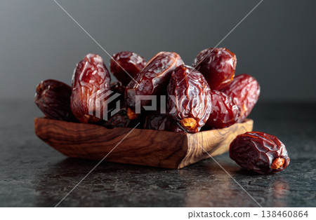 Dates fruit in wooden dish on a black background. 138460864