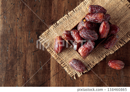 Dried dates fruit in wooden dish on a wooden table. Dried dates fruit in wooden dish on a wooden table. 138460865