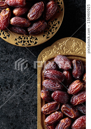 Dates fruits in a golden bowls on black stone table. Dates fruits in a golden bowls on black stone table. 138460925