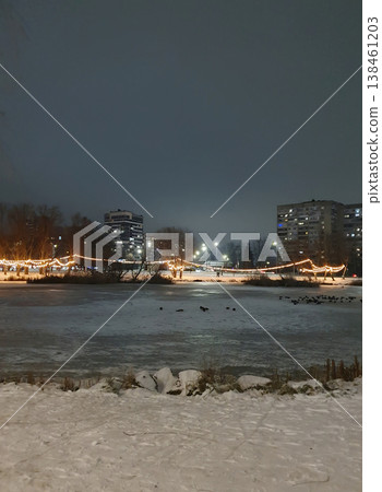 Winter city park in the evening, decorated with warm garlands on the trees. Snow on the ground, festive atmosphere of a winter night. For themes of Christmas, New Year, holidays coziness, winter walks Winter city park in the evening, decorated with warm garlands on the trees. Snow on the ground, festive atmosphere of a winter night. For themes of Christmas, New Year, holidays coziness, winter walks 138461203